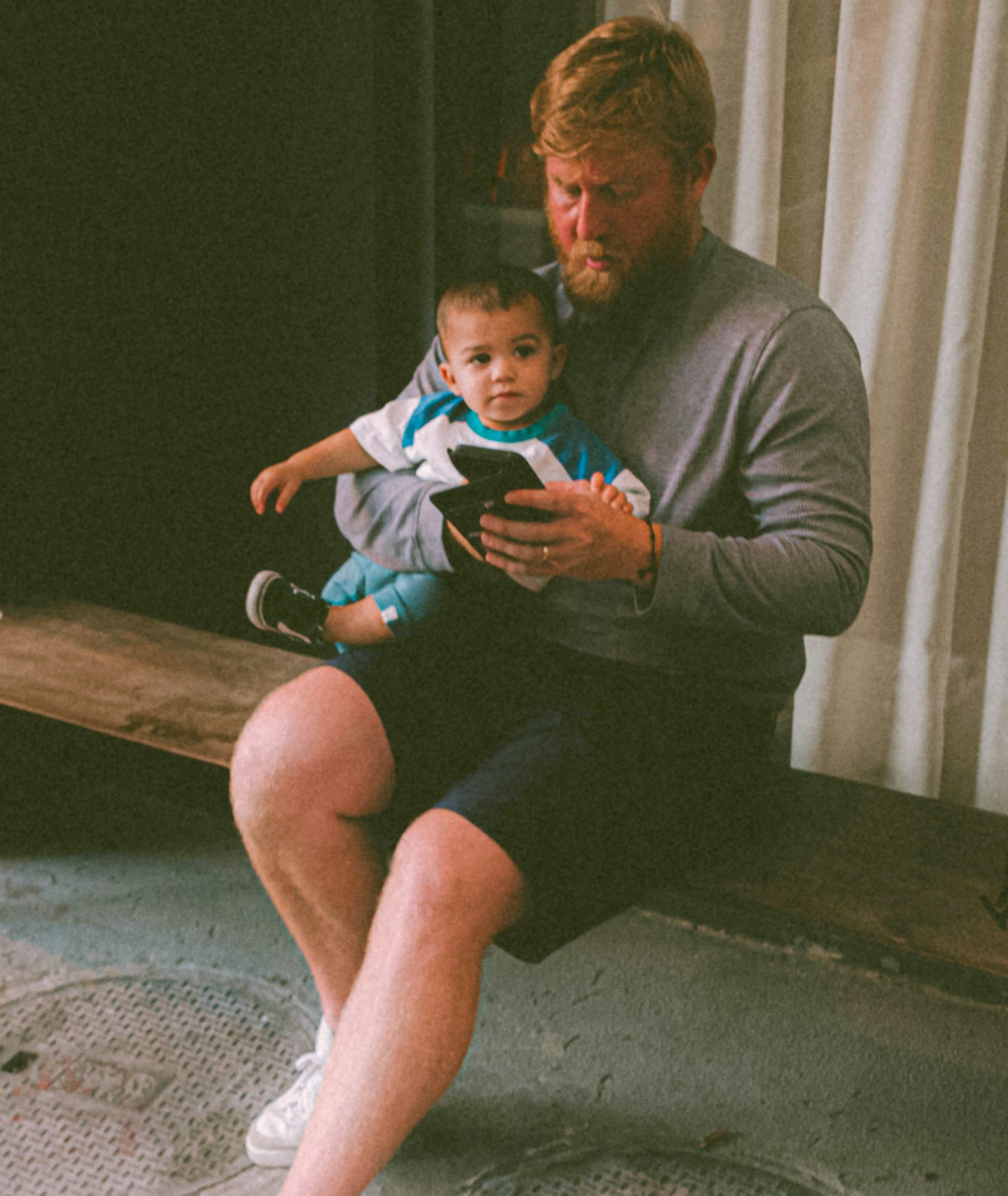 Father holding his young child while paying an orthopedic medical bill on his mobile phone