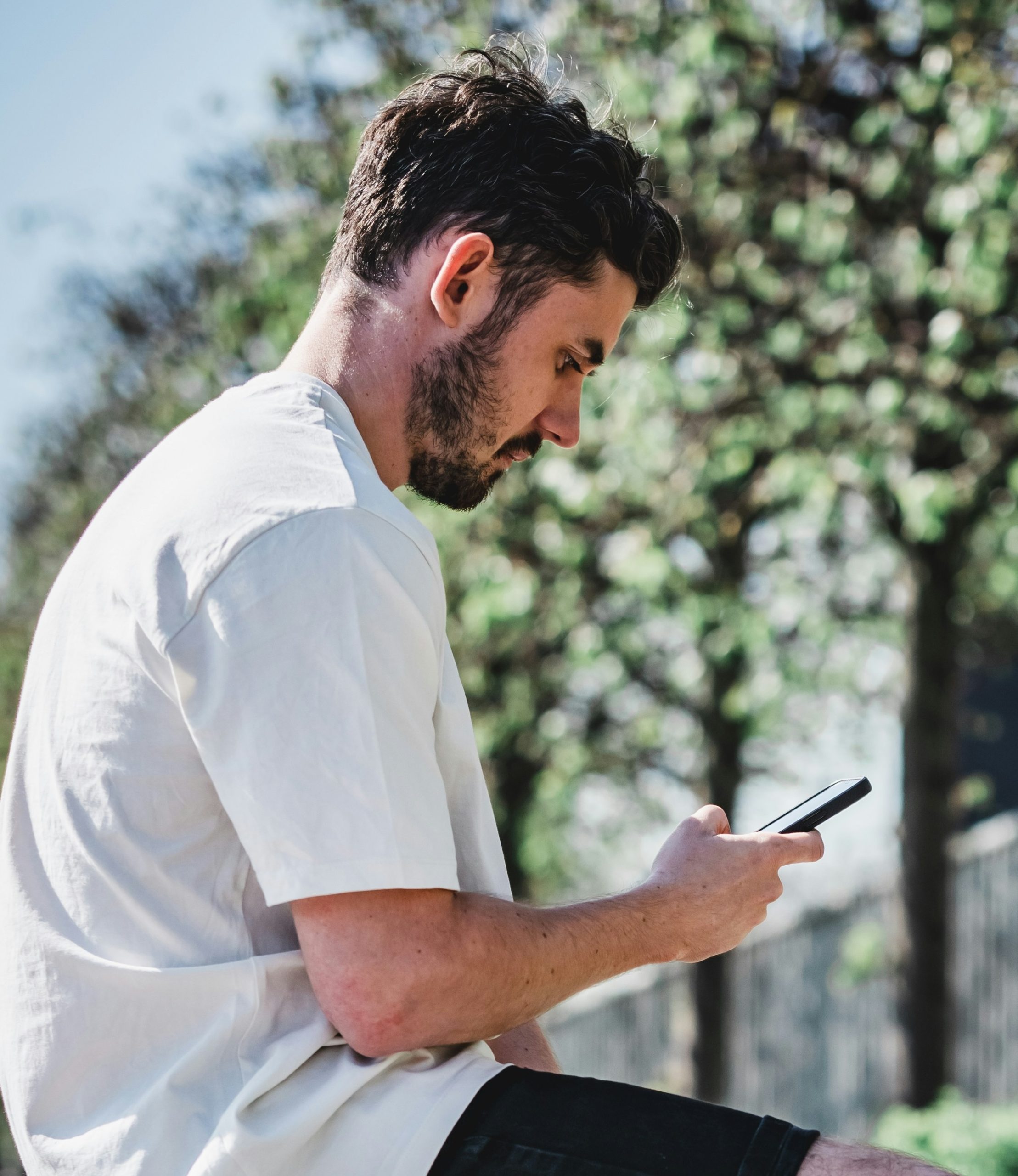 A young man reviewing and paying a medical bill on his phone outdoors